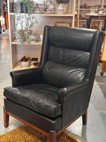 Black upholstered wingback armchair with wooden legs